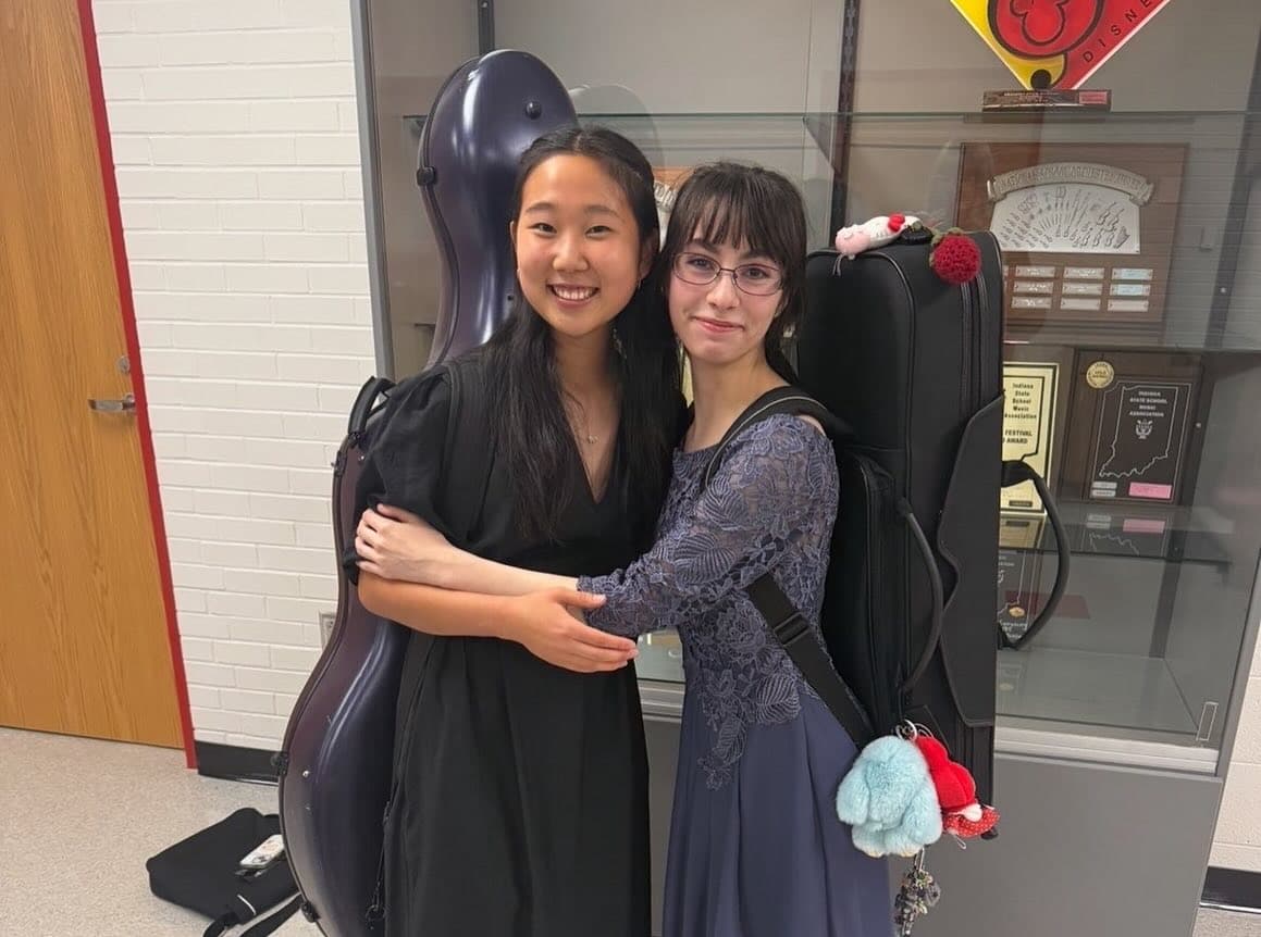 Two Munster students standing beside the orchestra trophy case